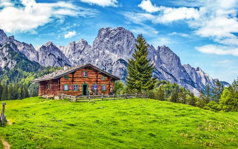 Idyllische Landschaft in den Alpen mit Berghütte und grünen Wiesen